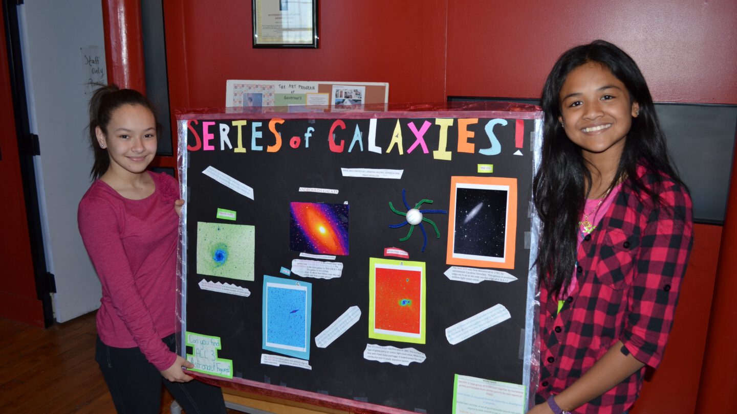 Two girls holding project board