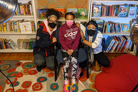 3 females in masks in library
